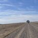Gravel road under expansive blue sky to barn